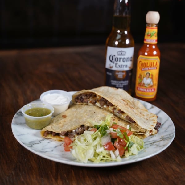 Two quesadillas with meat and cheese, salsa, sour cream, salad, a Corona, and Cholula hot sauce.