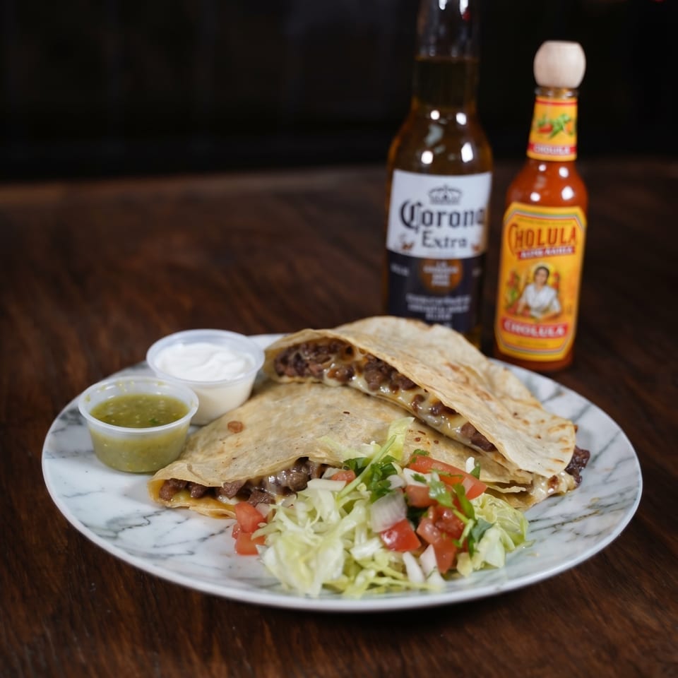 Two quesadillas with meat and cheese, salsa, sour cream, salad, a Corona, and Cholula hot sauce.