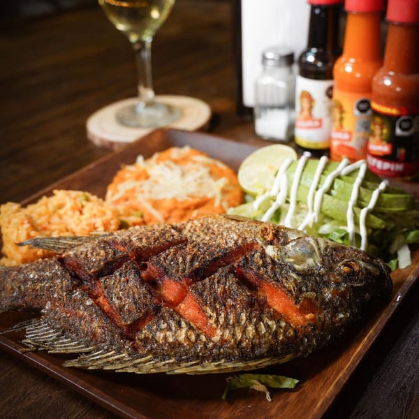 Whole fried fish with rice, refried beans, avocado, and lime, served with hot sauces and wine.