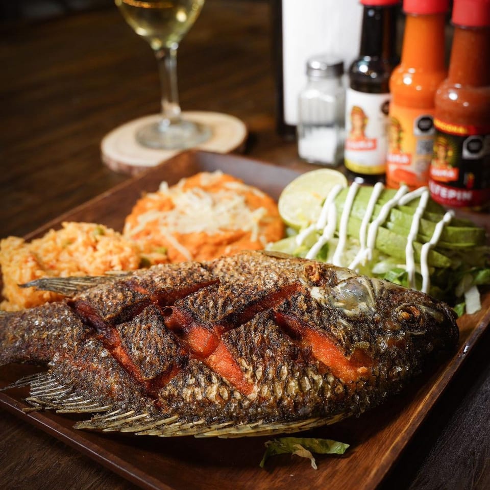 Whole fried fish with rice, refried beans, avocado, and lime, served with hot sauces and wine.